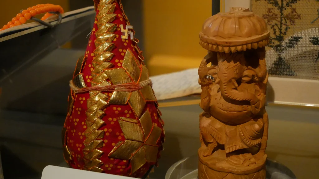Decorated coconut and Ganesha figure displayed as Hindu home-puja objects in a museum