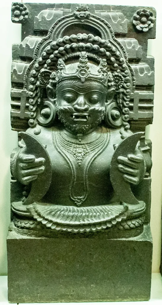 Stone Navagraha relief of Rahu holding crescent forms associated with the Moon.